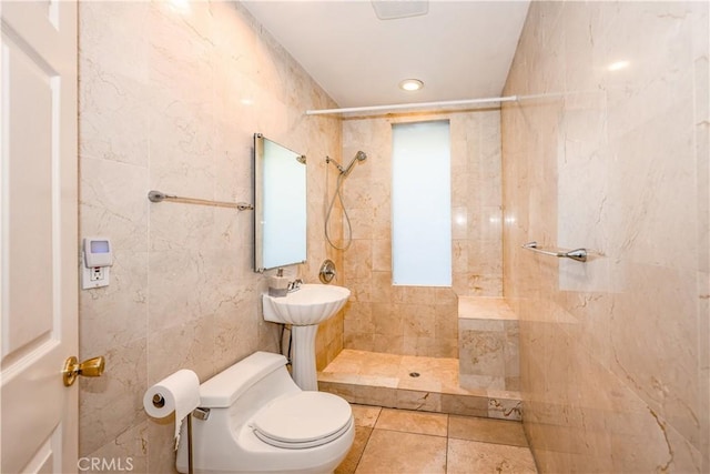 full bathroom featuring tiled shower, toilet, tile walls, and tile patterned flooring