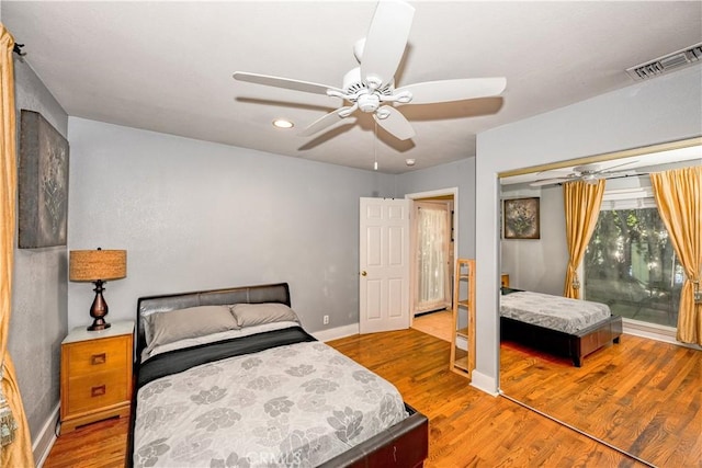 bedroom with visible vents, ceiling fan, baseboards, wood finished floors, and a closet