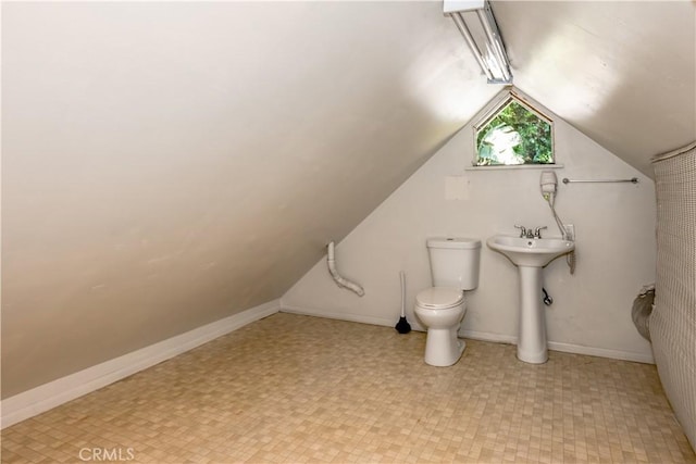 bathroom featuring vaulted ceiling, toilet, baseboards, and a sink