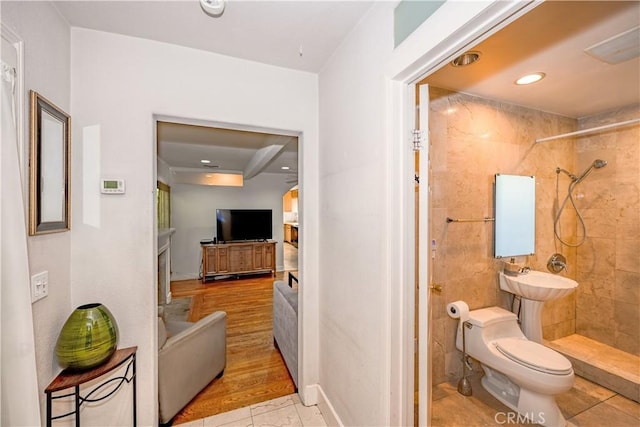 bathroom featuring a tile shower, recessed lighting, and toilet