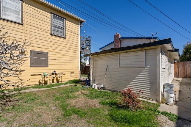 view of side of home with an outdoor structure and fence