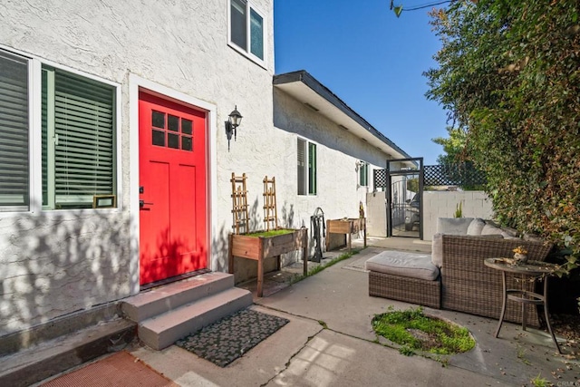 property entrance with stucco siding, a patio, and fence