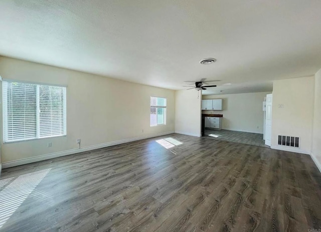 unfurnished living room with baseboards, wood finished floors, visible vents, and ceiling fan