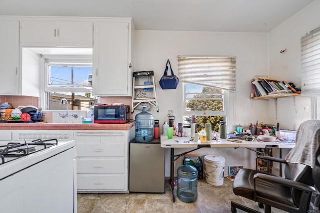 381214 36th St, San Diego, CA 92104 - kitchen with white range with gas stovetop, freestanding refrigerator, white cabinetry, decorative backsplash, and tile counters