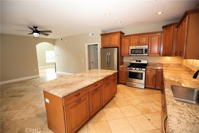 kitchen with visible vents, brown cabinetry, arched walkways, stainless steel appliances, and a sink