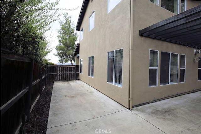 view of side of property with a patio area, a fenced backyard, and stucco siding