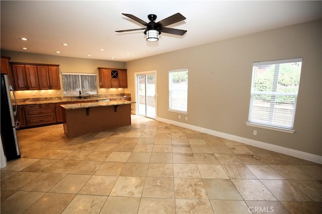 kitchen featuring a kitchen island, a breakfast bar, a healthy amount of sunlight, and freestanding refrigerator