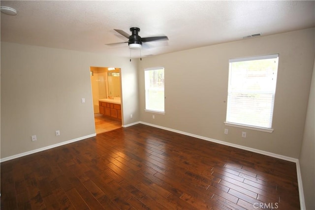 unfurnished room with visible vents, a ceiling fan, a textured ceiling, dark wood finished floors, and baseboards