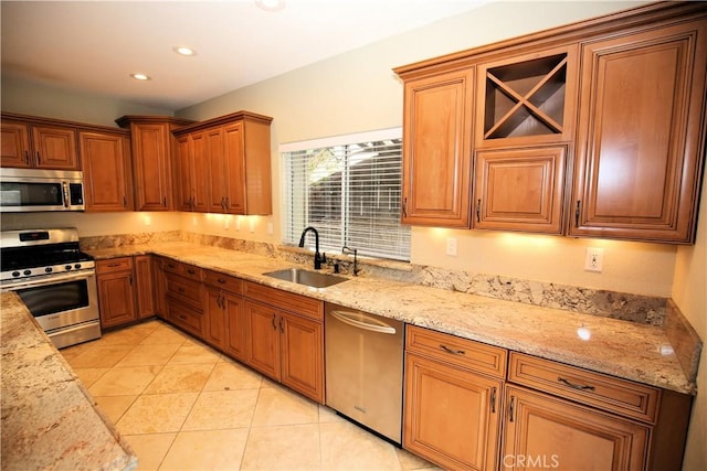 kitchen with a sink, light stone counters, recessed lighting, stainless steel appliances, and light tile patterned floors