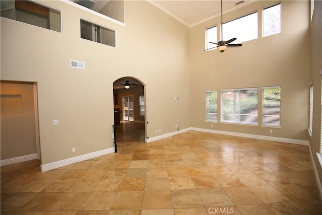 unfurnished room featuring visible vents, arched walkways, baseboards, and a ceiling fan