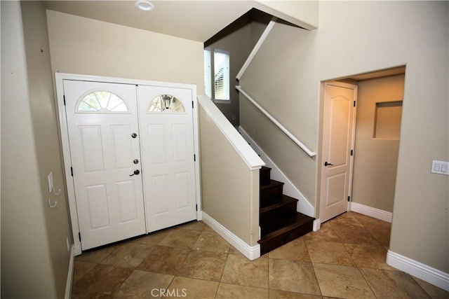 foyer entrance with stairway and baseboards