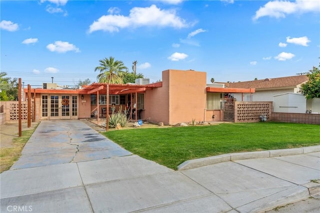 view of front of home with stucco siding, french doors, a front lawn, and fence