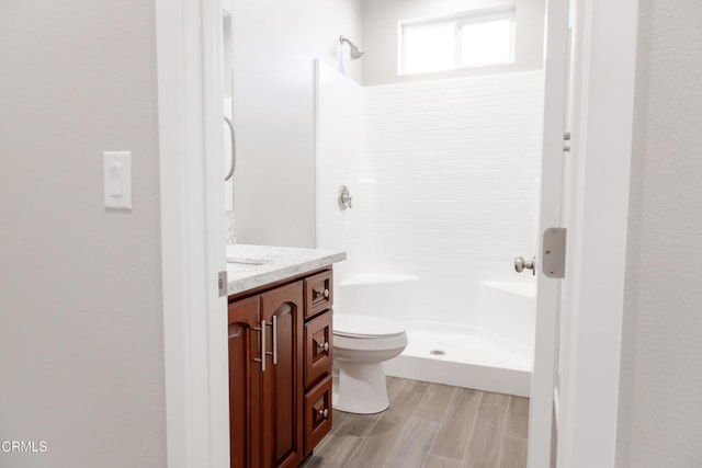 full bathroom featuring vanity, toilet, a stall shower, and wood tiled floor