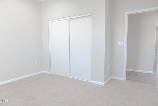 unfurnished bedroom with a closet, carpet floors, and baseboards