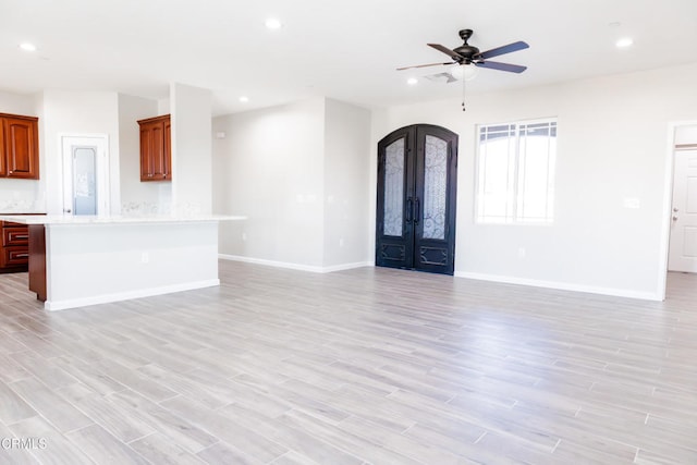 unfurnished living room featuring recessed lighting, french doors, arched walkways, light wood finished floors, and baseboards