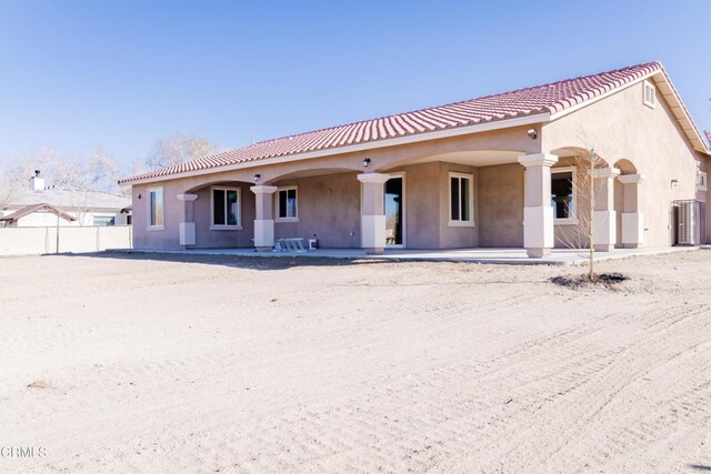 rear view of house featuring cooling unit, stucco siding, a tiled roof, and fence