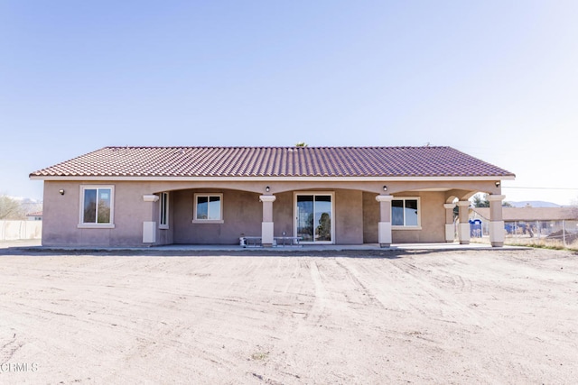 rear view of house featuring a tiled roof and stucco siding