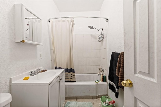 bathroom featuring toilet, vanity, shower / tub combo, and a textured wall