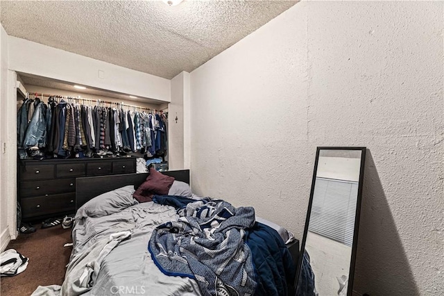 carpeted bedroom featuring a textured wall and a textured ceiling