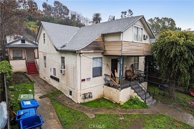 view of front of home featuring a porch, cooling unit, and a shingled roof