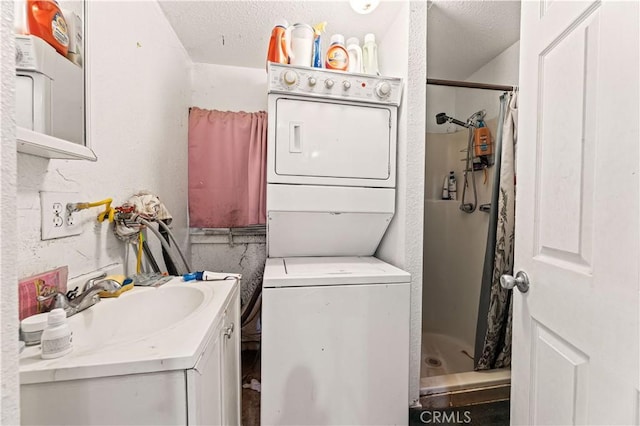 laundry room featuring a sink, a textured ceiling, stacked washer / drying machine, laundry area, and a textured wall