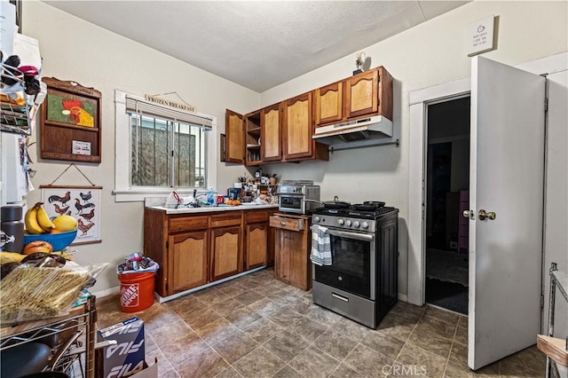 kitchen with baseboards, light countertops, under cabinet range hood, gas range, and brown cabinets