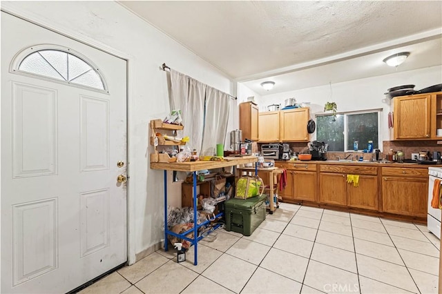 kitchen with range, brown cabinets, backsplash, and light tile patterned flooring