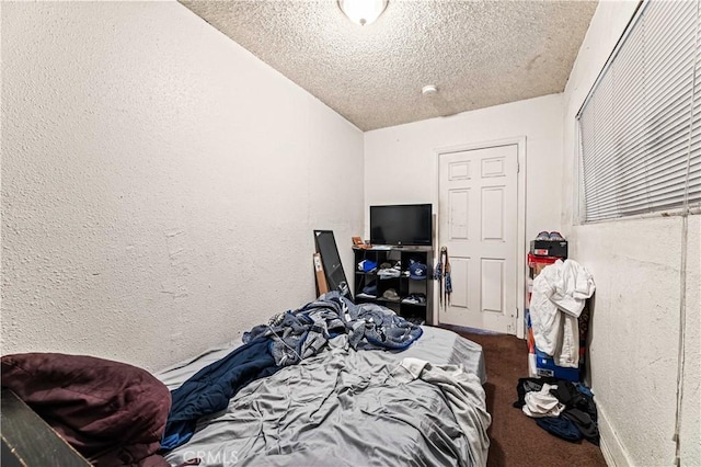 carpeted bedroom featuring a textured ceiling and a textured wall