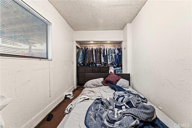 carpeted bedroom with a textured ceiling, baseboards, and a textured wall