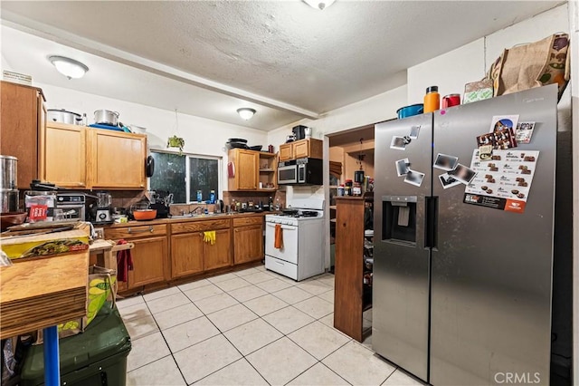 kitchen featuring brown cabinets, open shelves, a textured ceiling, appliances with stainless steel finishes, and light tile patterned floors