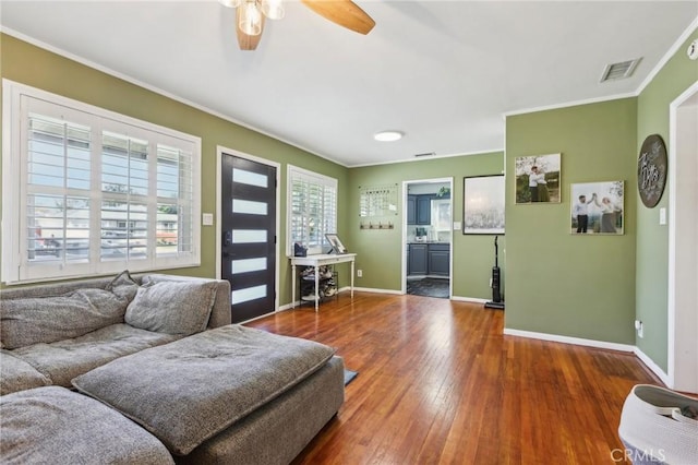 living room with visible vents, ornamental molding, hardwood / wood-style flooring, baseboards, and ceiling fan