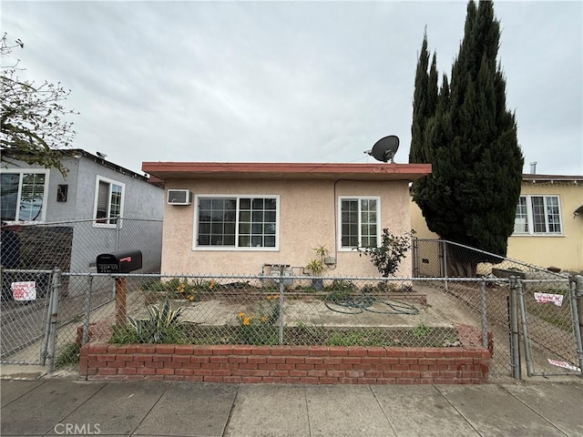 view of front of home with stucco siding, an AC wall unit, and fence private yard