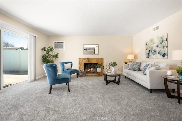 carpeted living room with a high end fireplace, visible vents, and a wall mounted AC