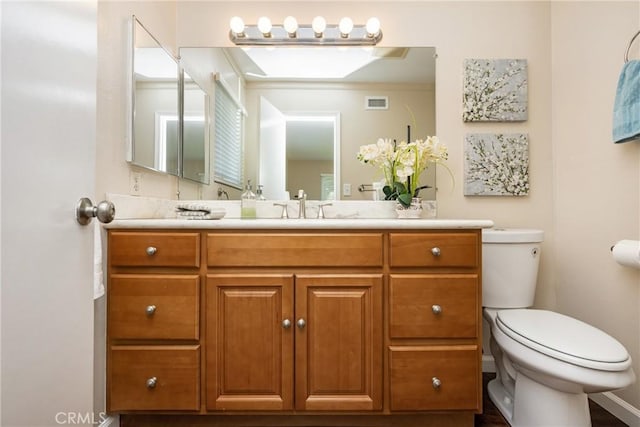 bathroom featuring vanity, toilet, and visible vents