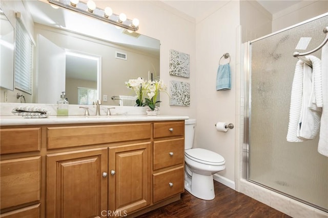 bathroom with visible vents, toilet, a stall shower, wood finished floors, and vanity