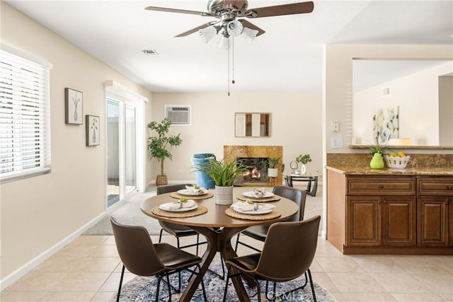 dining area with visible vents, baseboards, light tile patterned flooring, a fireplace, and an AC wall unit