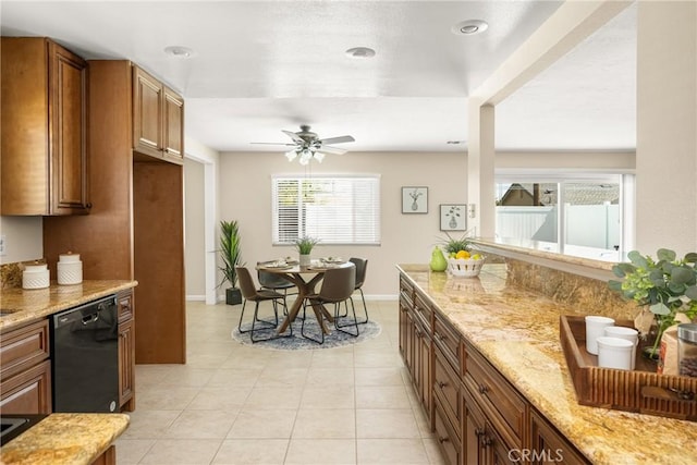 kitchen with light tile patterned floors, brown cabinets, black dishwasher, and light stone countertops