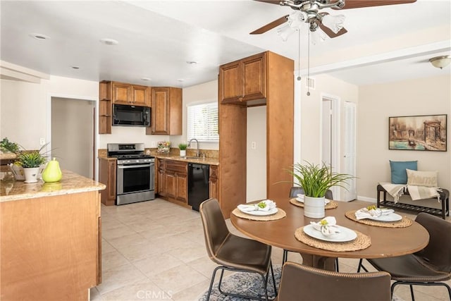 kitchen featuring brown cabinetry, black appliances, light stone counters, and a sink