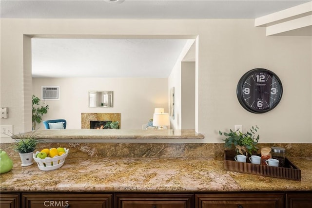 interior space featuring dark brown cabinets, an AC wall unit, a fireplace, and light countertops