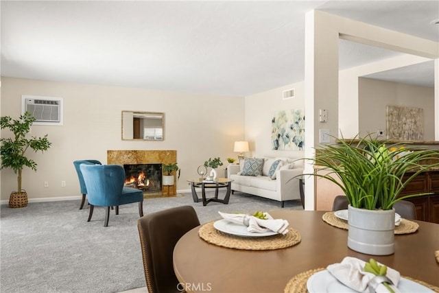 carpeted living room with a wall mounted air conditioner, visible vents, baseboards, and a fireplace