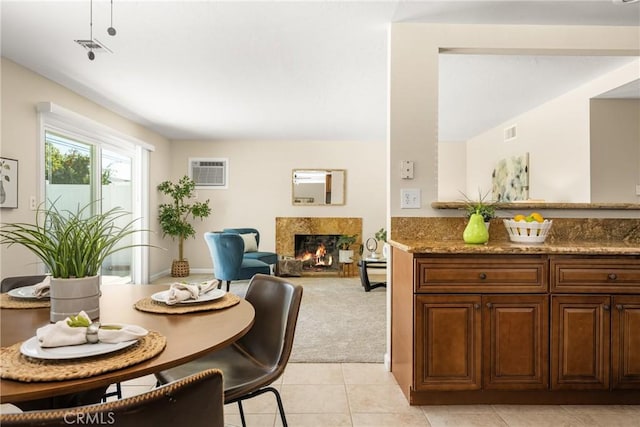 dining room featuring visible vents, light tile patterned flooring, a high end fireplace, an AC wall unit, and light colored carpet