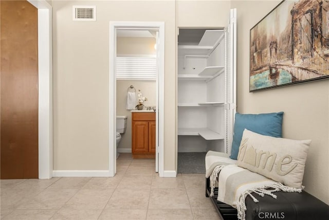 living area featuring light tile patterned floors, visible vents, and baseboards