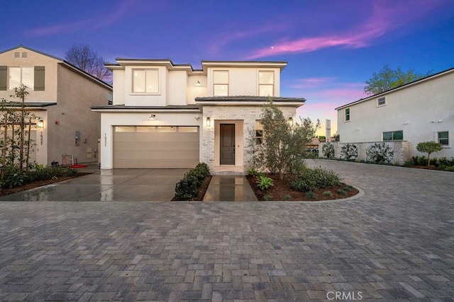 view of front of home with stucco siding, brick siding, a garage, and concrete driveway