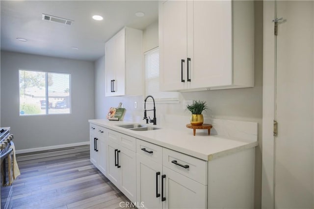 kitchen featuring visible vents, a sink, light countertops, gas range oven, and light wood-type flooring