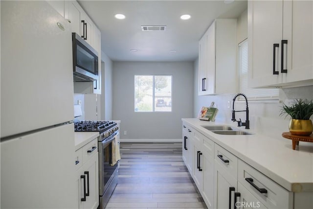 kitchen with visible vents, a sink, appliances with stainless steel finishes, light wood finished floors, and light countertops