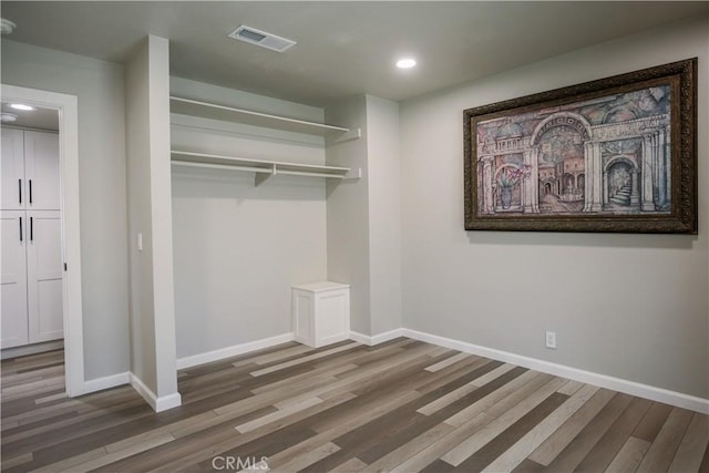 unfurnished bedroom with wood finished floors, visible vents, baseboards, recessed lighting, and a closet