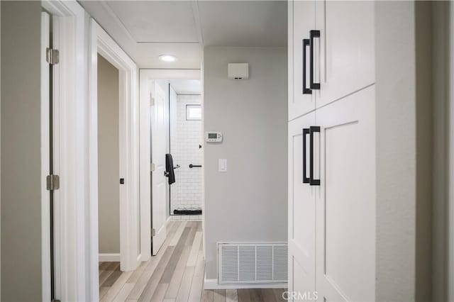 corridor with visible vents, baseboards, and light wood-style floors