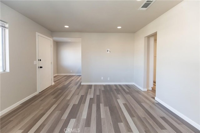 empty room featuring recessed lighting, wood finished floors, visible vents, and baseboards