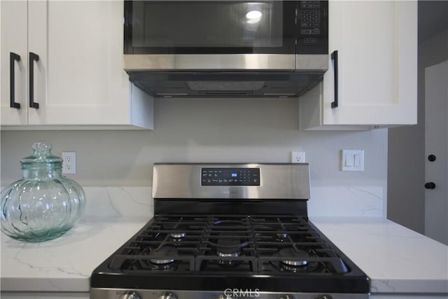 kitchen with white cabinetry, ventilation hood, light stone countertops, and stainless steel appliances