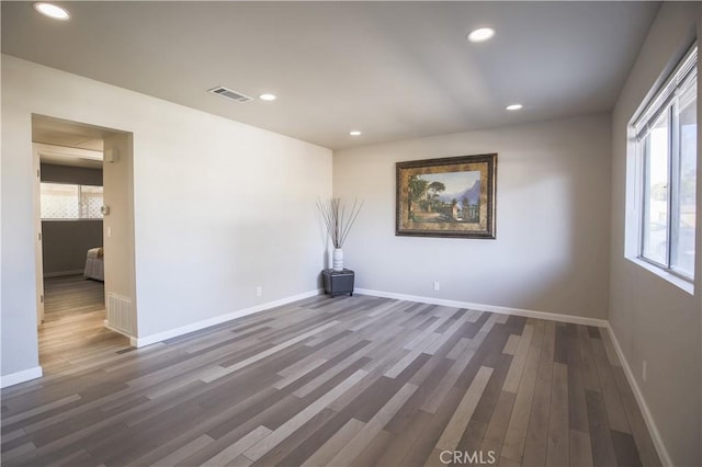 unfurnished room with wood finished floors, recessed lighting, visible vents, and baseboards